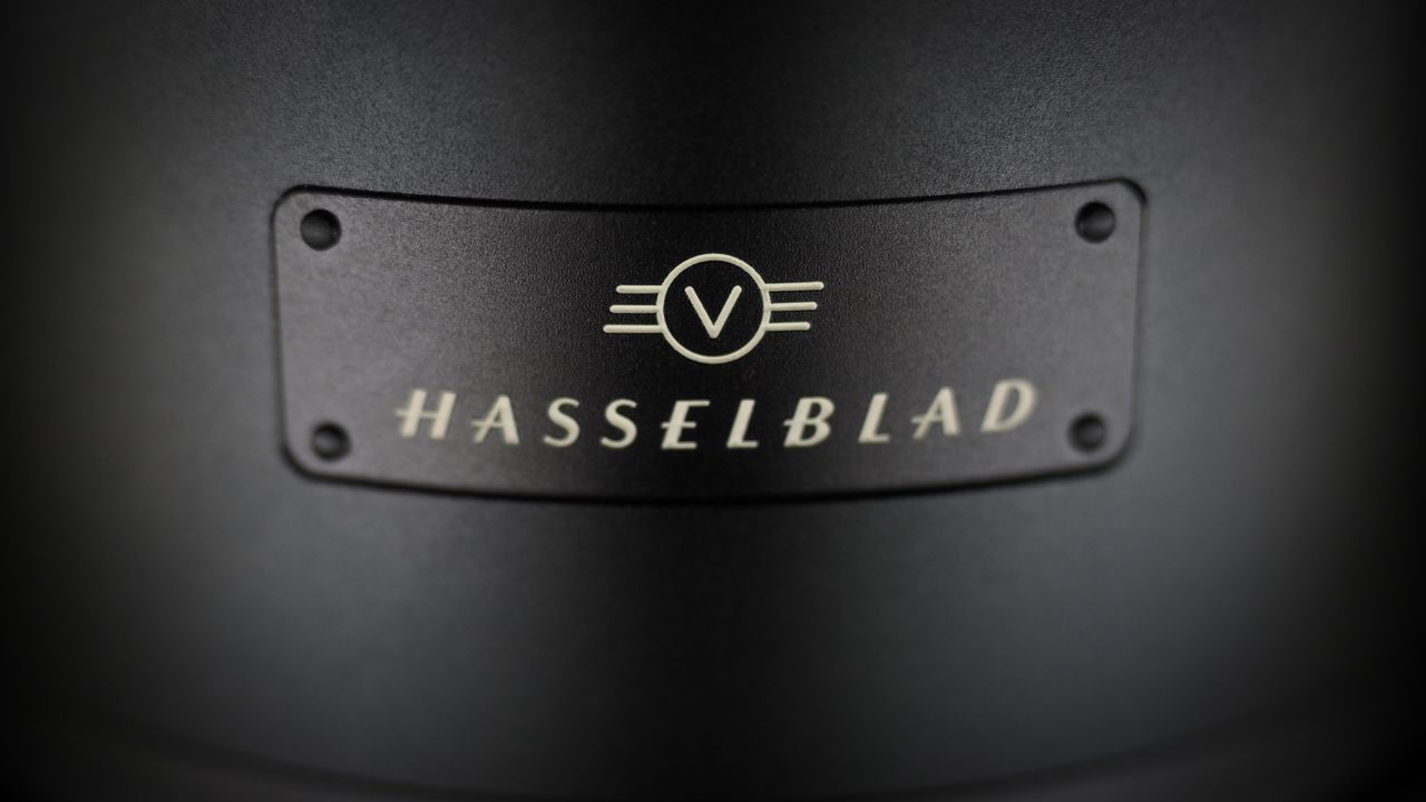 Hasselblad XCD 25V lens, on a wooden table, shot with dramatic light against a dark background