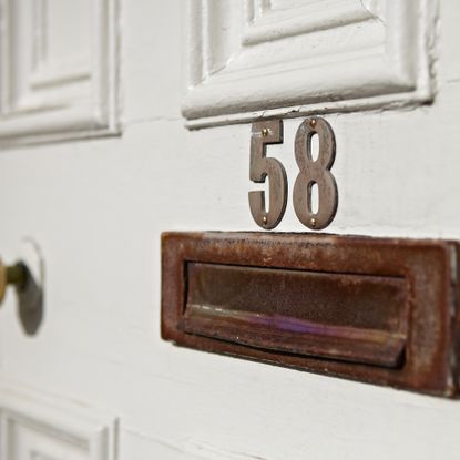 Close up of rusted letterbox and house number on door
