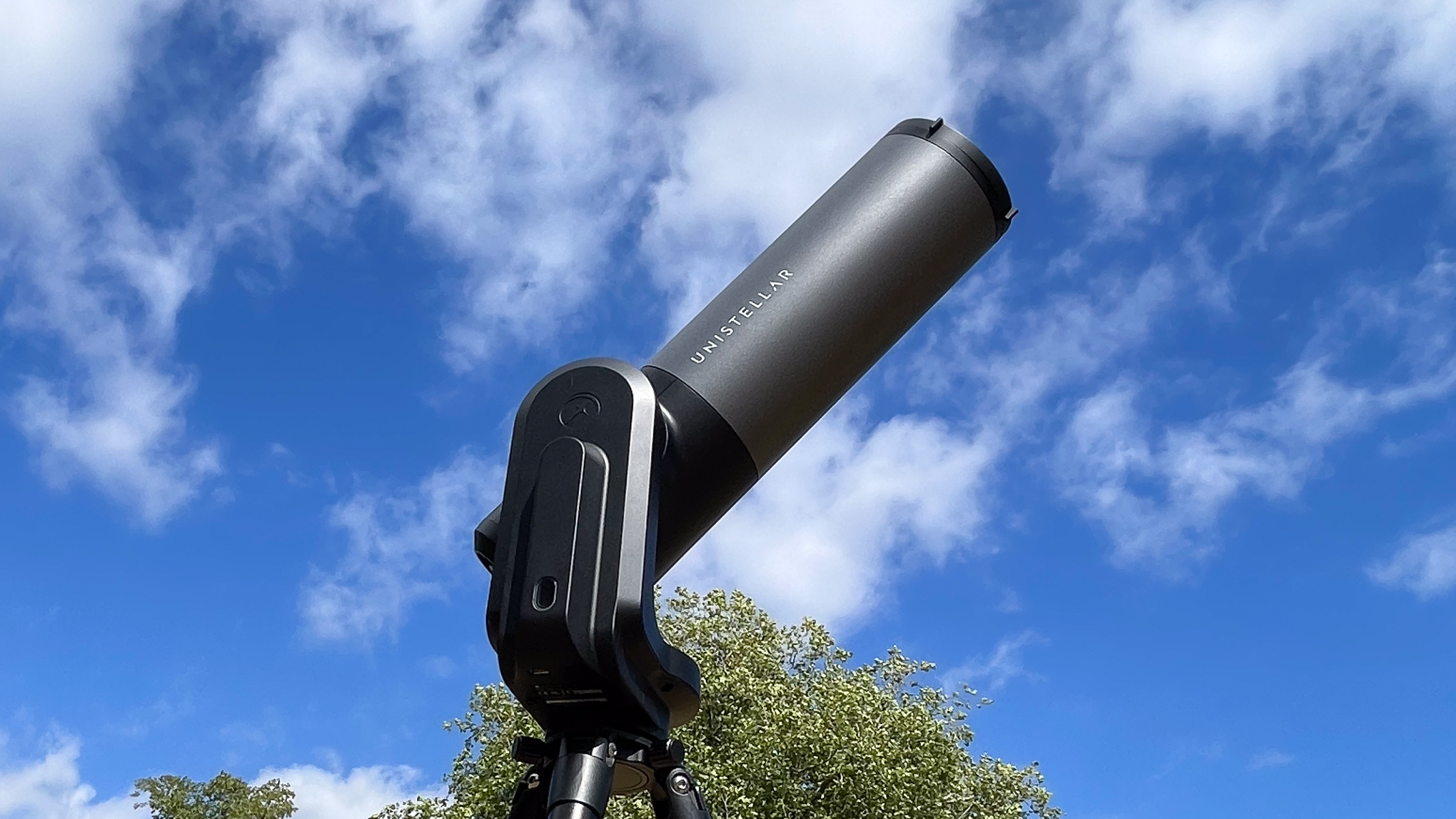 A Unistellar eVscope 2 against a cloudy blue sky.