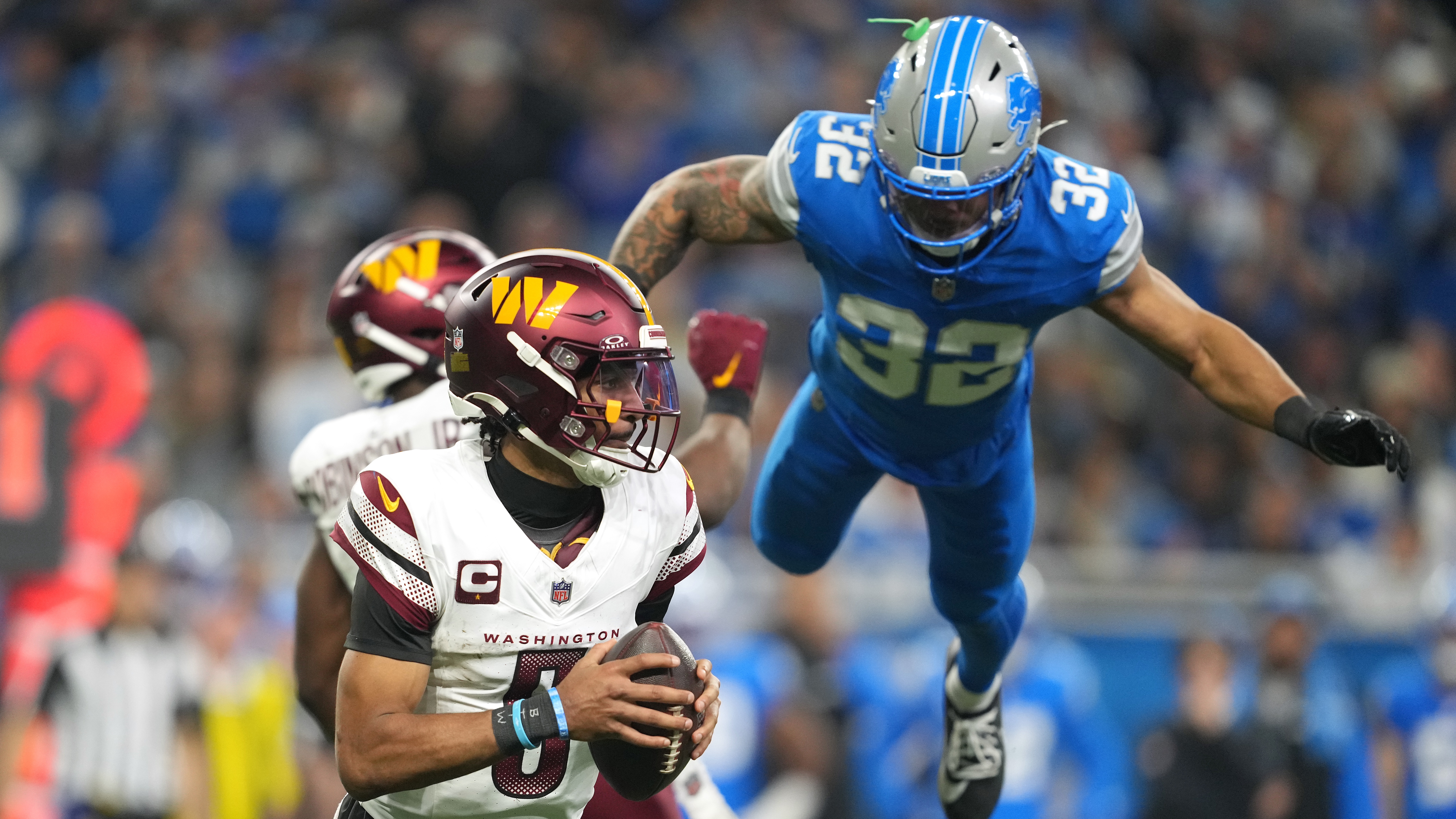 Jayden Daniels #5 of the Washington Commanders scrambles with the ball as Brian Branch #32 of the Detroit Lions dives to apply pressure during the third quarter in the NFC Divisional Playoff at Ford Field on January 18, 2025 in Detroit, Michigan.