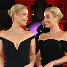 Amelia and Eliza Spencer wearing off-the-shoulder black gowns and diamond necklaces while smiling at each other