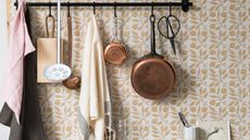 Floral kitchen with hanging copper pots, white ladles, and cream and pink dish towels