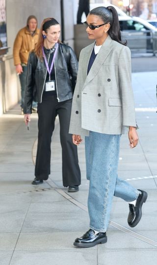 Simone Ashley wears a white tee with a v-neck jumper and double-breasted blazer.