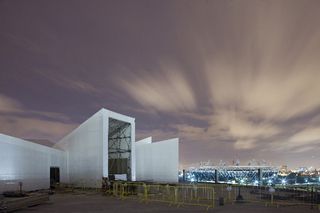 A large white structure with a stadium behind it.