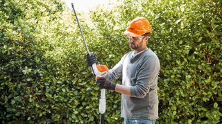 Stihl hedge trimmer in use by a man, attaching a telescopic pole