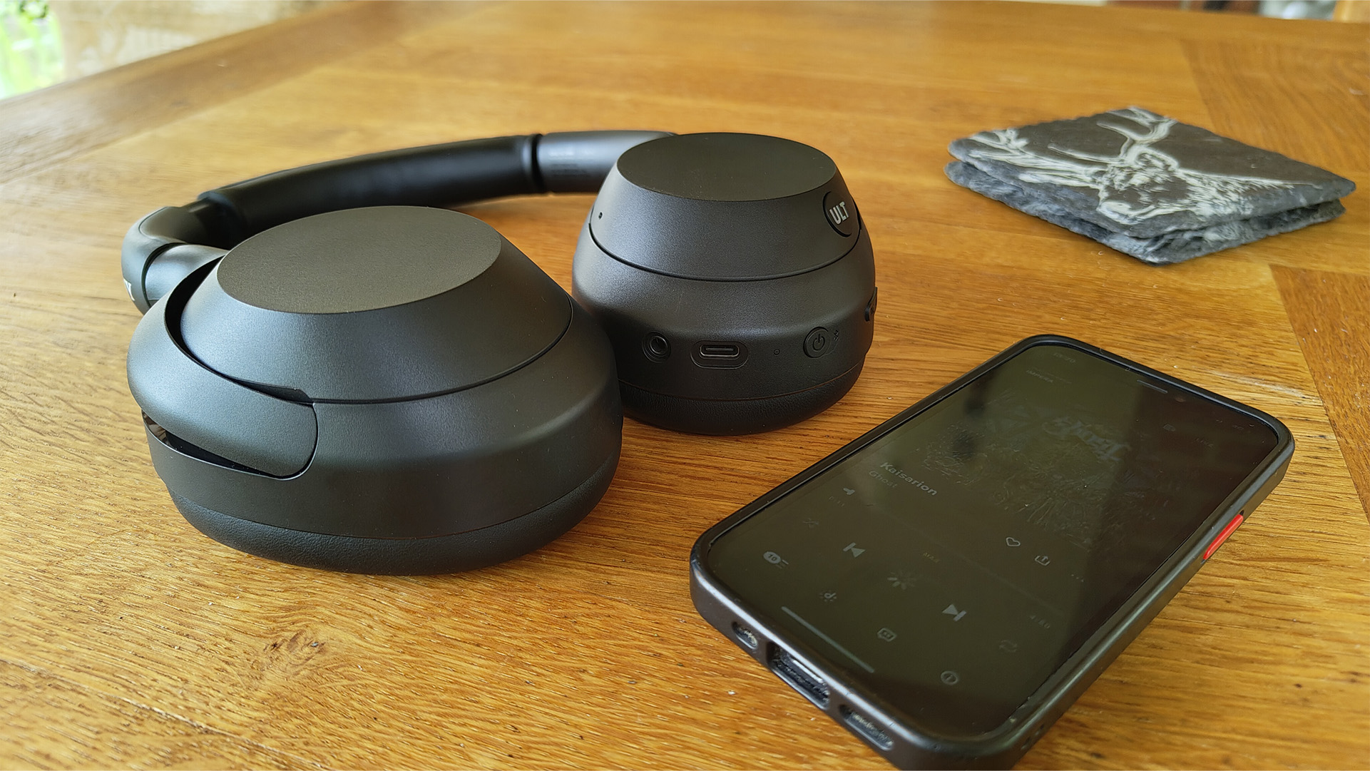 Sony ULT Wear over-ear headphones on wooden table next to smartphone
