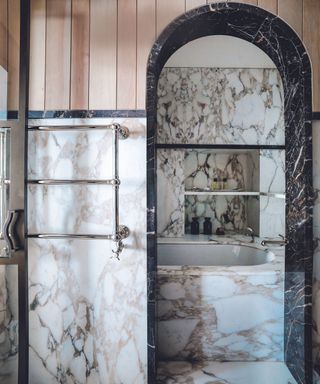 Marble bathroom with arch behind which the bathtub sits