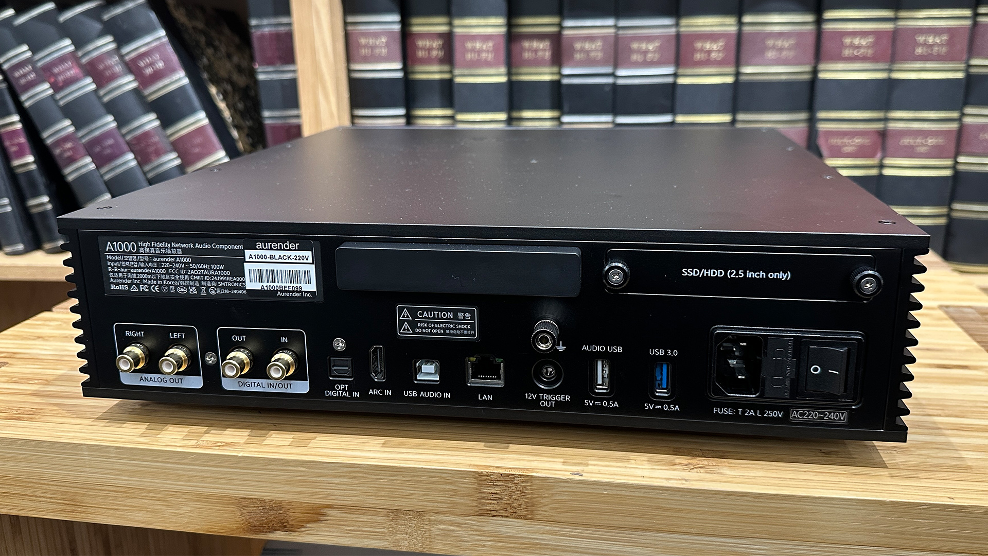 Aurender A1000 music streamer on wooden hi-fi rack in front of bookcase rear of unit showing connections