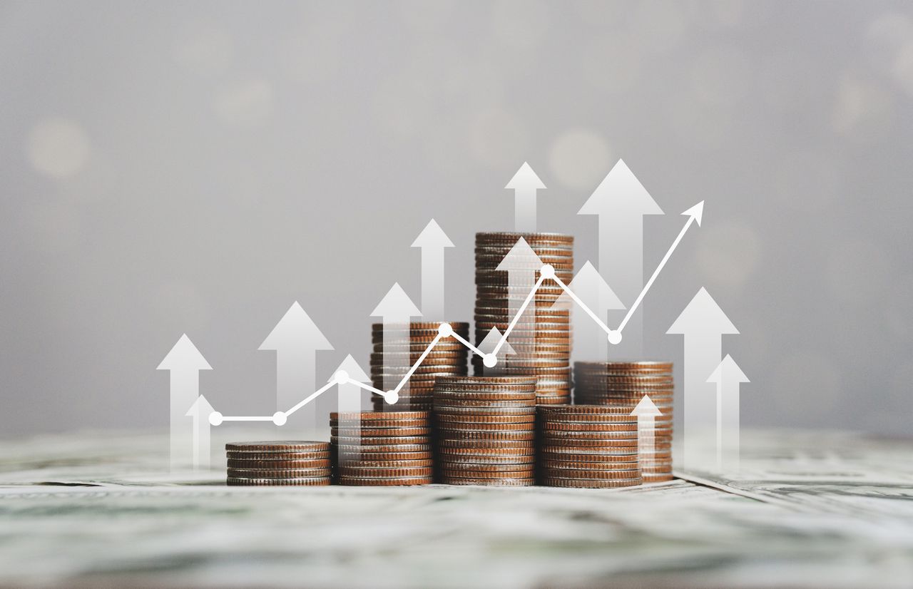 Stacks of coins with a graphic of a positive stock chart and arrows pointing up.