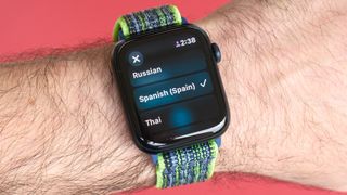 Close-up photo of an Apple Watch SE 2022 against a red background with the new Translate app displayed on the screen