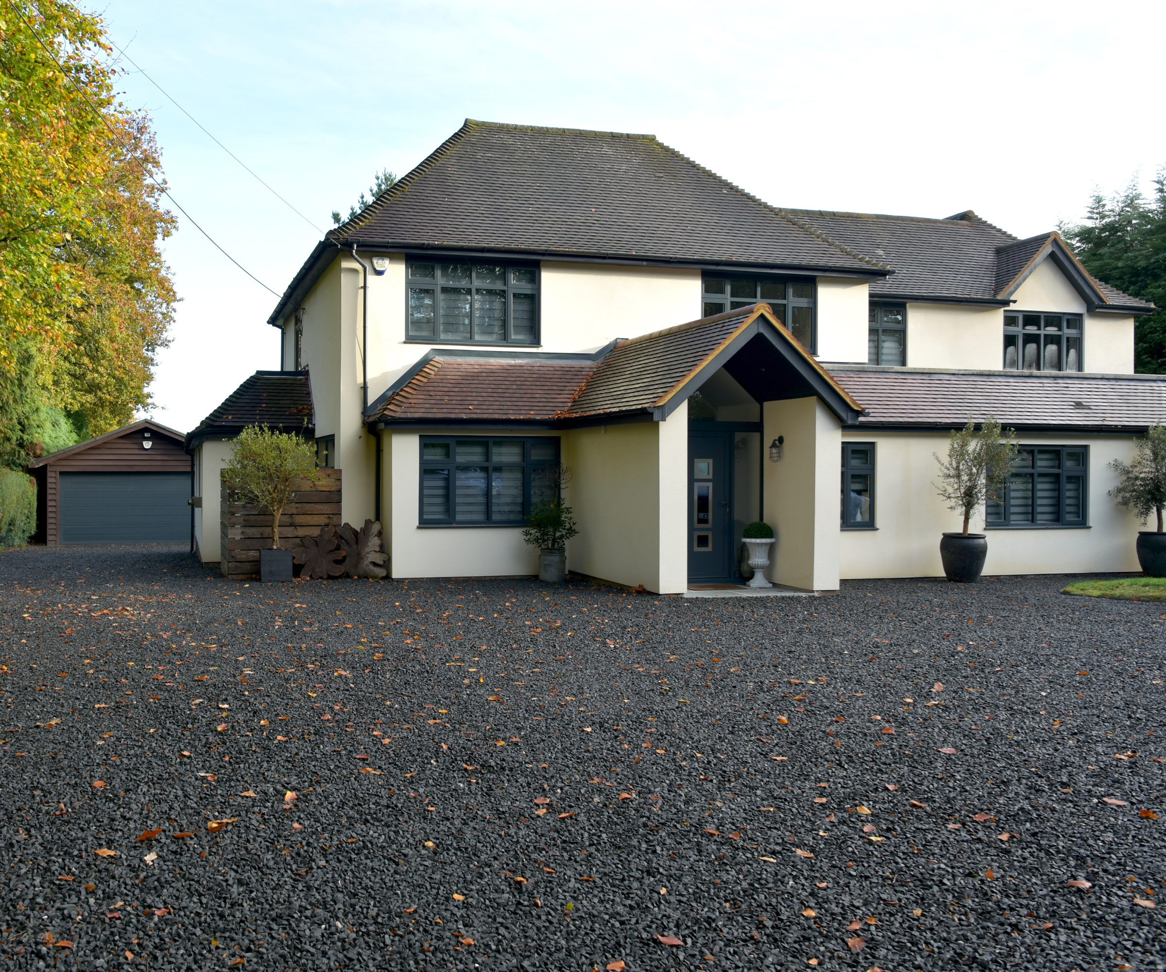 House with dark window panes, roof and door, with a dark gravel in front