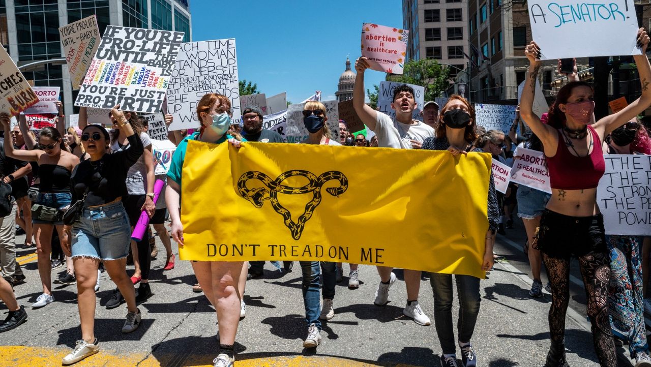 Protesters hold up signs as they march down Congress Ave at a protest or the heartbeat bill outside the Texas state capitol on May 29, 2021 in Austin, Texas. 