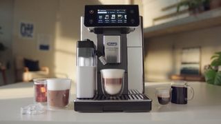 The De'Longhi PrimaDonna Aromatic surrounded by cups 