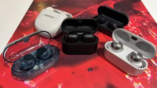 A selection of wireless earbuds with their cases opened places on a red record cover