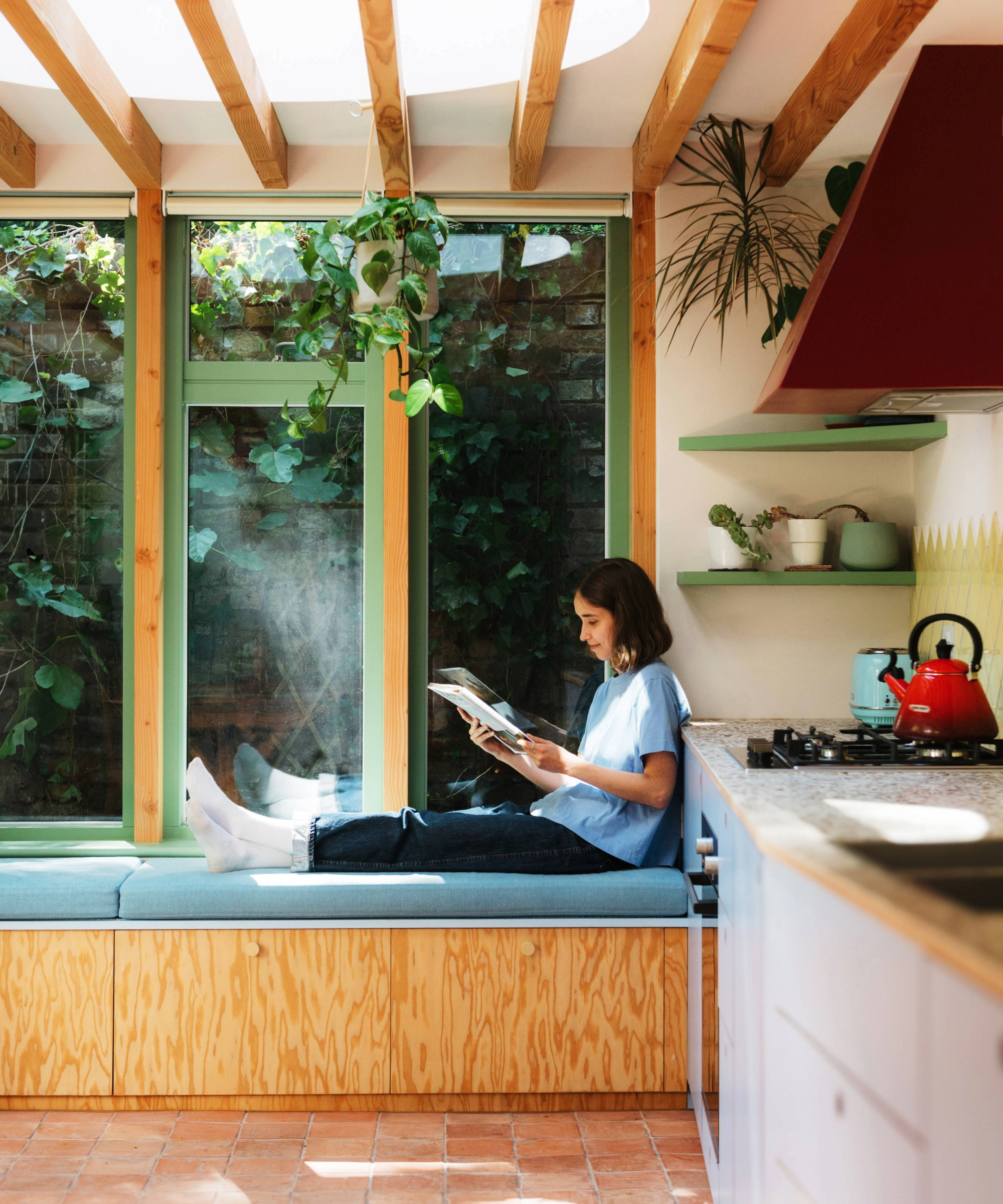 Woman sitting on the window nook in the kitchen reading a book