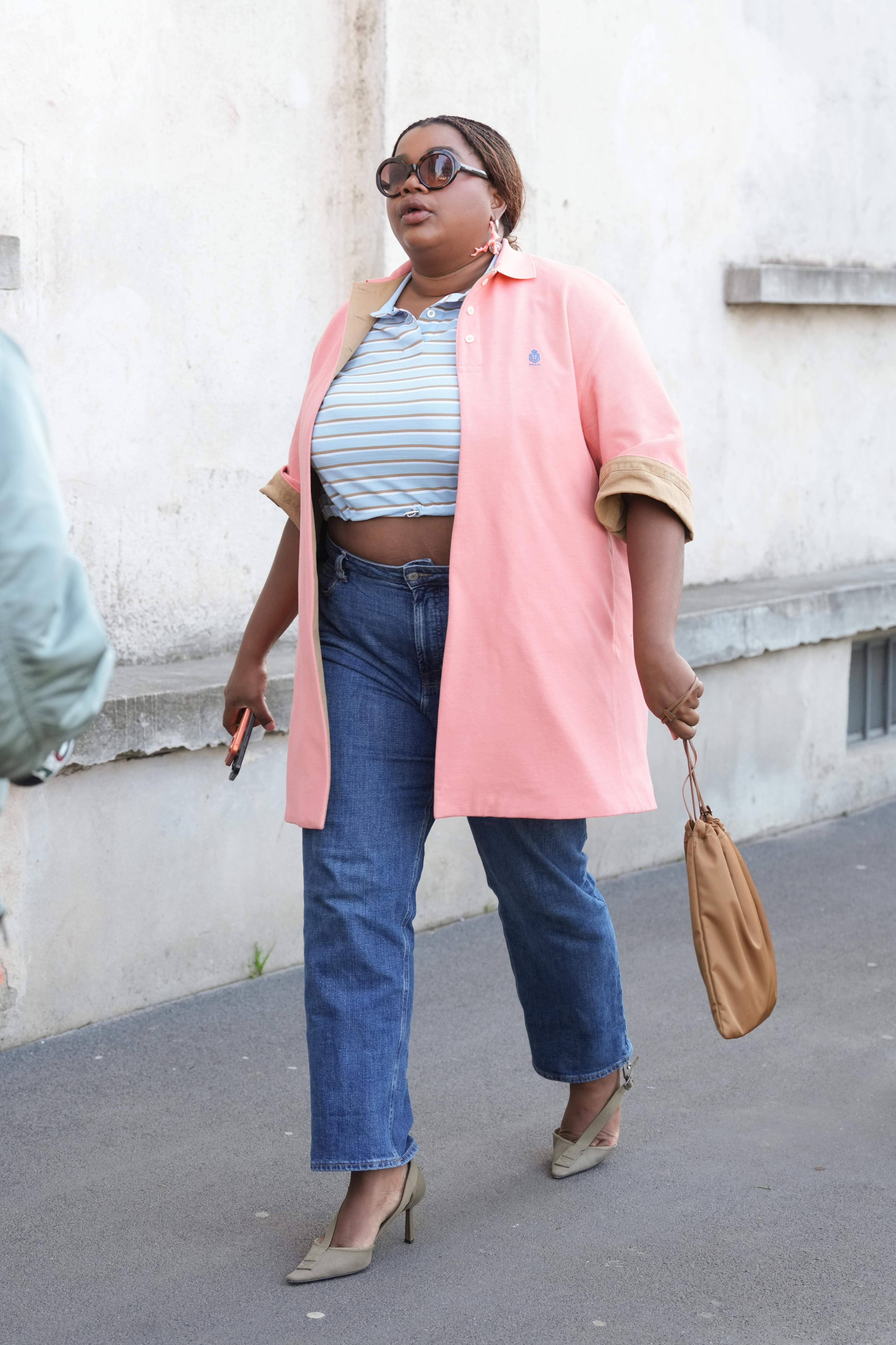 MILAN, ITALY - FEBRUARY 26: Gabriella Karefa Johnson is seen wearing a light pink long Prada coat, a striped cropped polo shirt, blue jeans, a beige handbag during the Milan Fashion Week - Womenswear Fall/Winter 2026/2027 on February 26, 2026 in Milan, Italy. (Photo by Alena Zakirova/Getty Images)