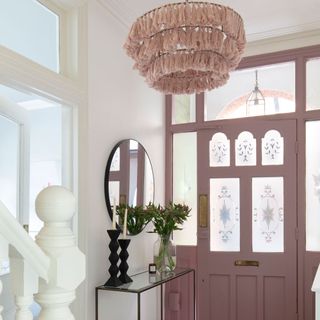 A hallway with a pink fabric light shade and a pink door