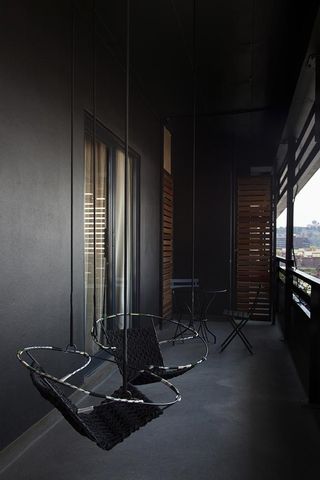 Black balcony with two black chairs hanging from the ceiling