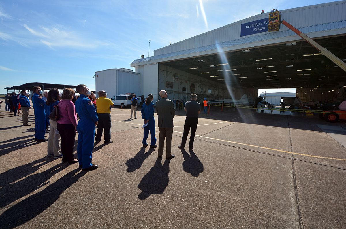 Workers on a cherry picker unveil the new sign naming NASA&#039;s Hangar 276 at Ellington Field in Houston as the &quot;Capt. John Young Hangar&quot; in honor of the late legendary astronaut.