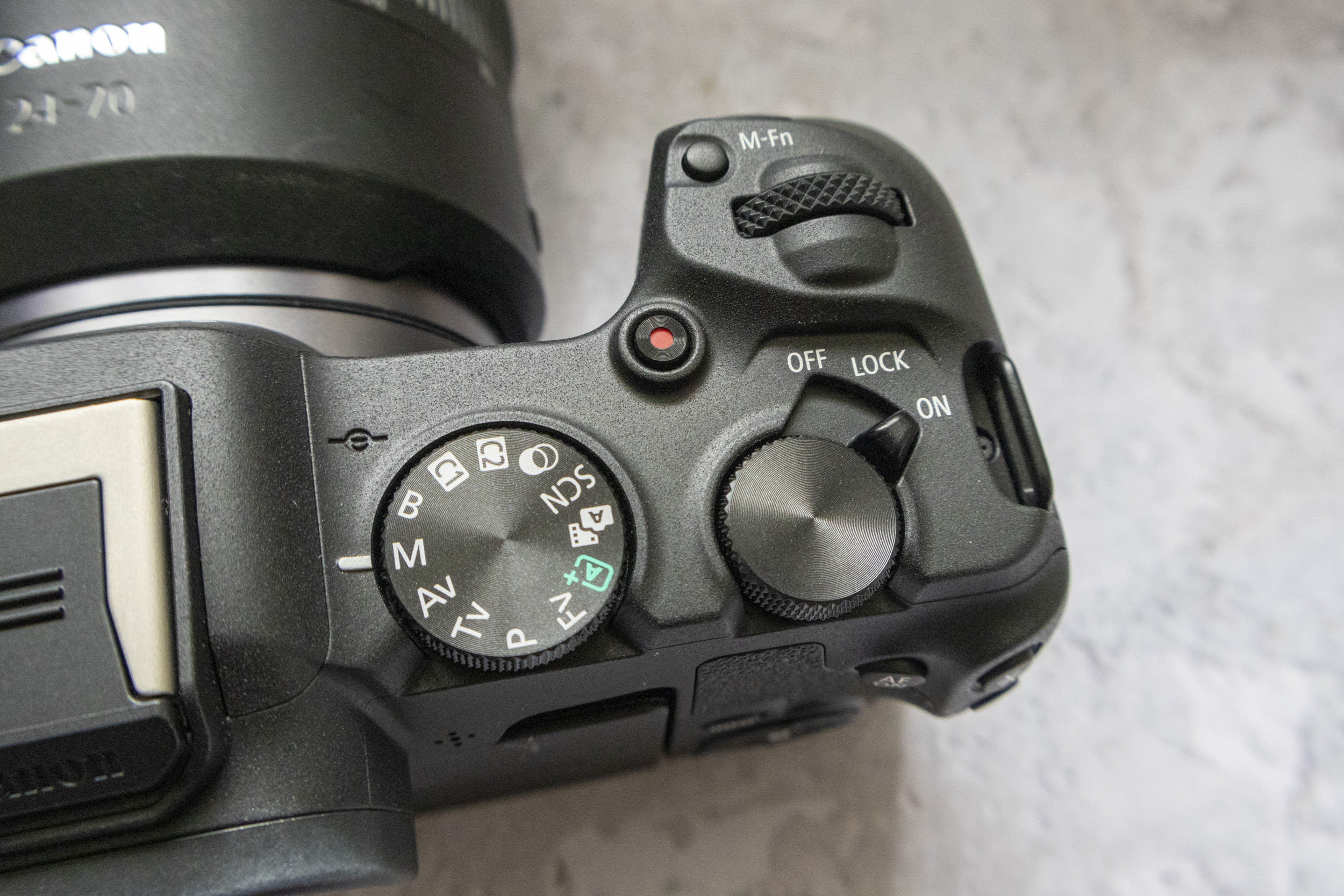 Canon EOS R8 camera on table and closeup of shooting mode dial with plain background