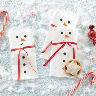 Christmas snowman napkins with red ribbons and candy canes on fake snow