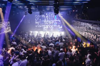 People dance in a club with bright lights and high-quality sound from DAS Audio.