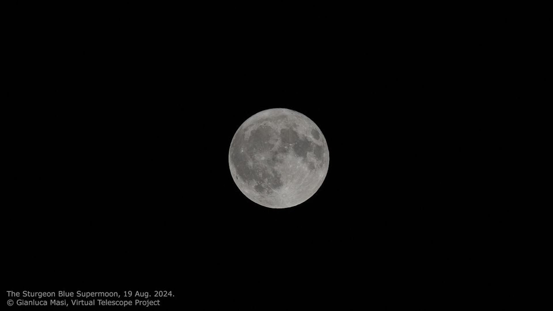 a fully illuminated moon against a black backdrop of sky.