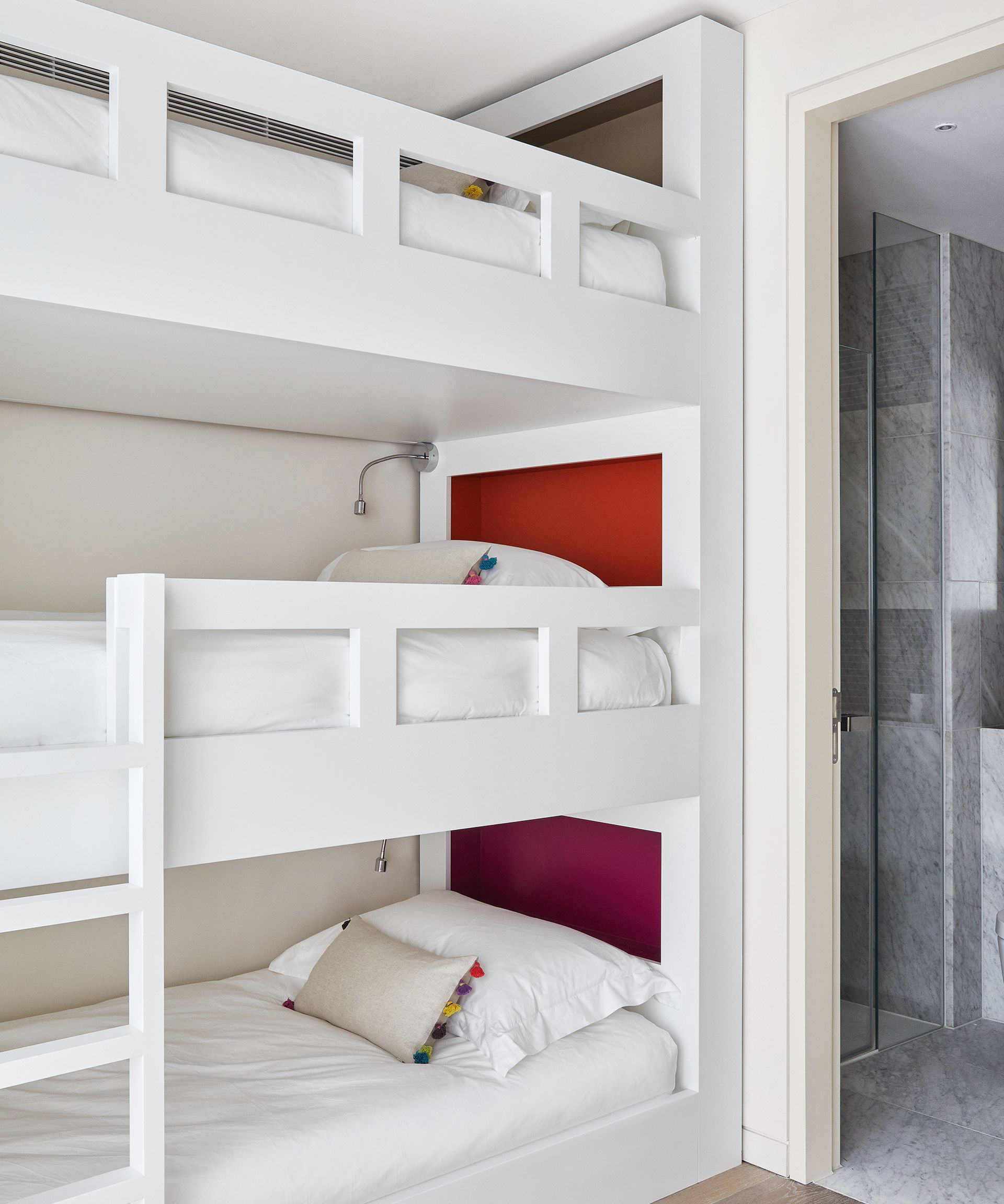 A triple bunk bed painted white with red headboards