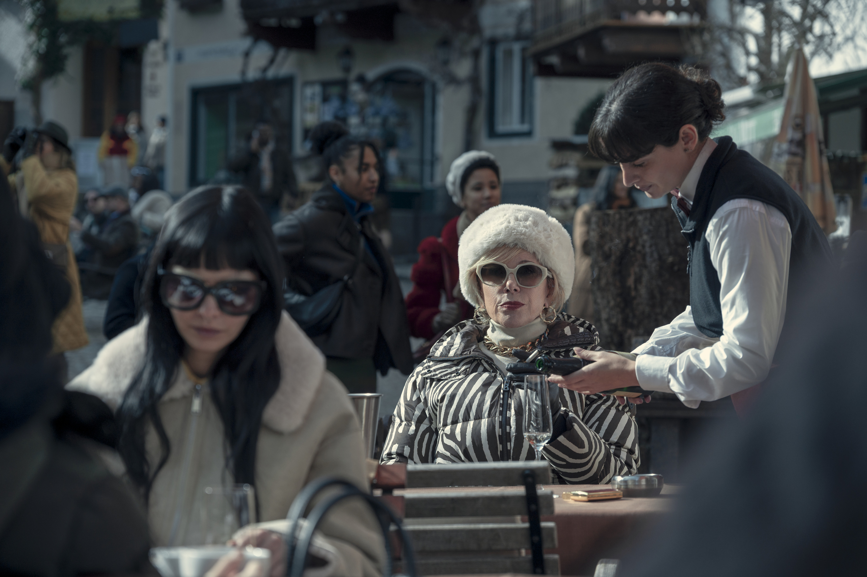 christine baranski as victoria wearing a white fur hat signing the bill at a restaurant in nine perfect strangers season 2