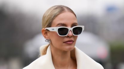 eyebrow shapes - Leonie Hanne wears white sunglasses from Celine, silver and rhinestones earrings from Balenciaga, a white latte oversized long belted coat, outside Coperni, during Paris Fashion Week - Womenswear F/W 2022-2023, on March 03, 2022 in Paris, France