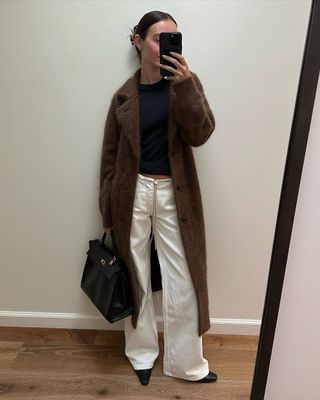 woman wearing white Still Here NYC jeans and brown long coat