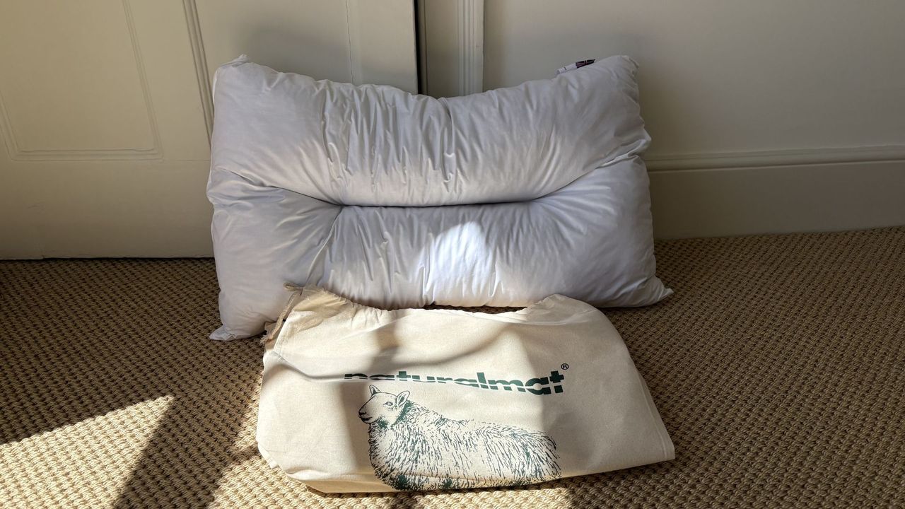 The Naturalmat The Centre Stitched Wool Pillow on a bed