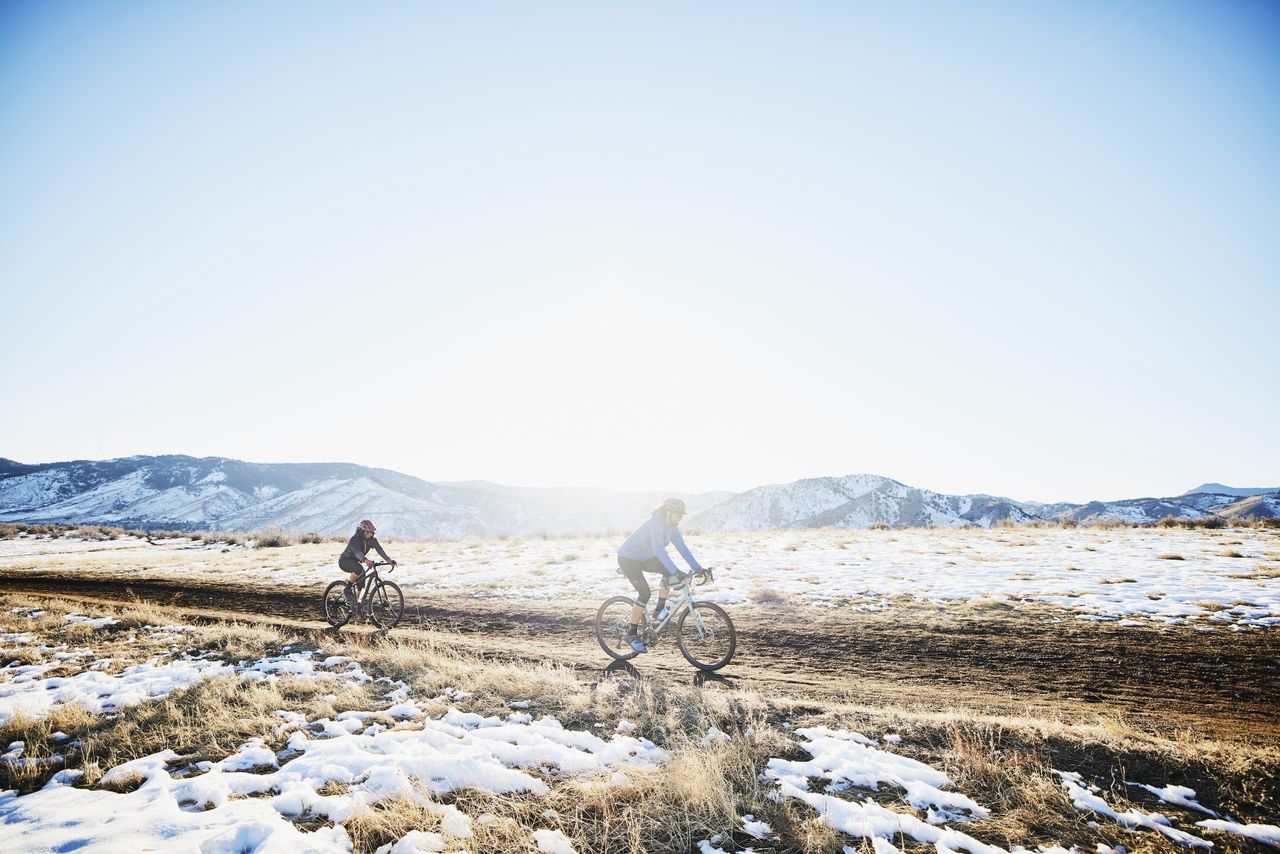 Two cyclists ride gravel in winter