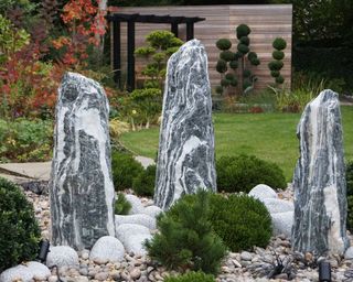 trio of tall stone boulders used as a decorative feature in a garden border