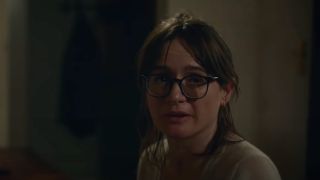 Emily Mortimer sitting at a piano, with glasses perched on her nose in Relic.