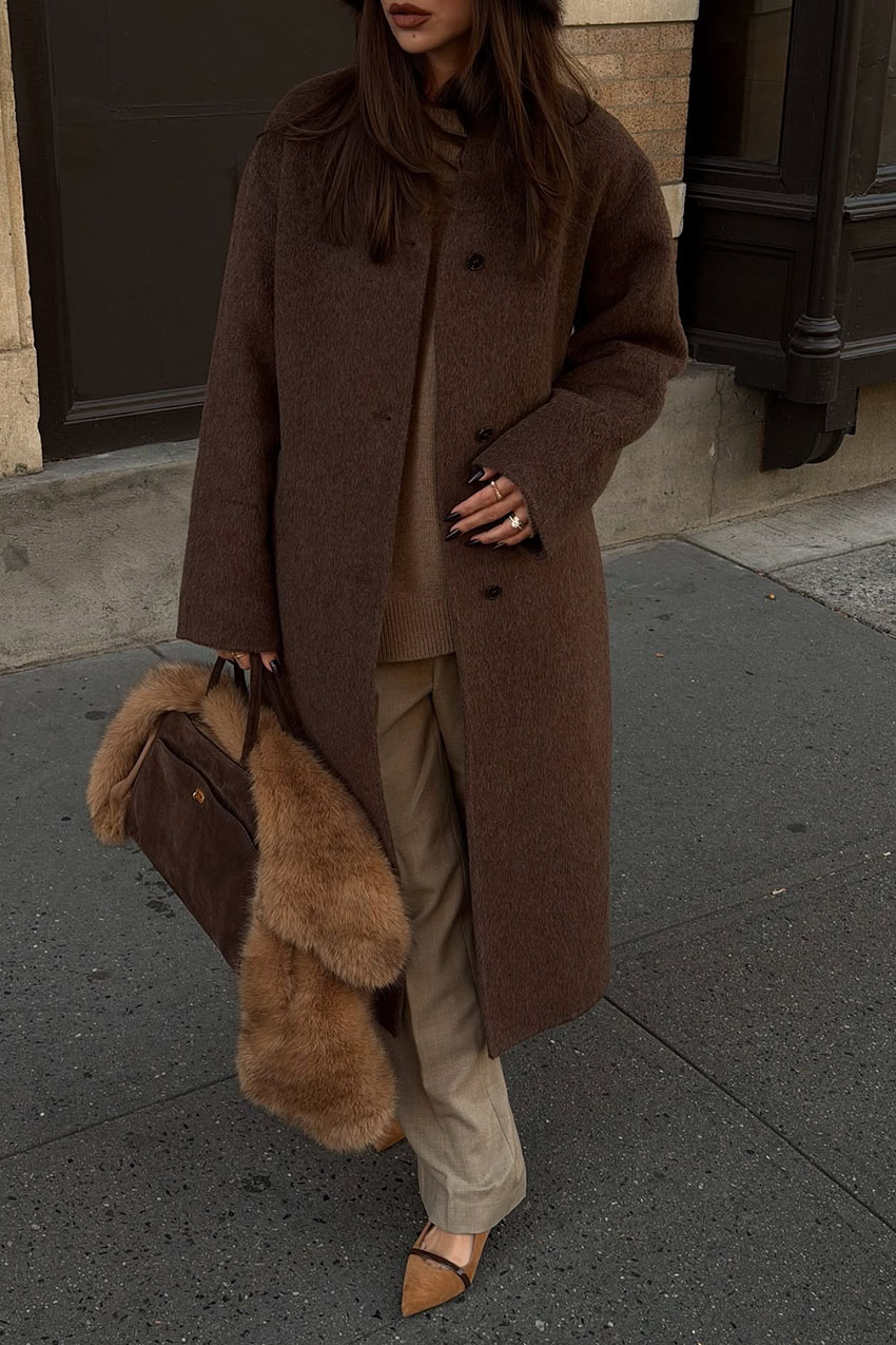a woman wearing a brown coat, brown bag, and fur scarf