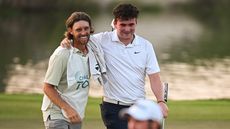 Tommy Fleetwood caddying for his stepson Oscar Craig (R) on the 9th hole, and celebrates after he plays his fourth shot and passed the cut during day two of the UAE Challenge at Saadiyat Beach Golf Club on April 26, 2024 in Abu Dhabi