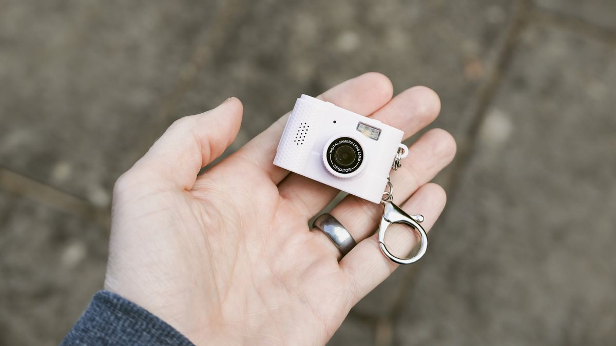 Miniature pink keychain camera, the 'Photo Creator Mini Digital Camera series 3', in user's hand