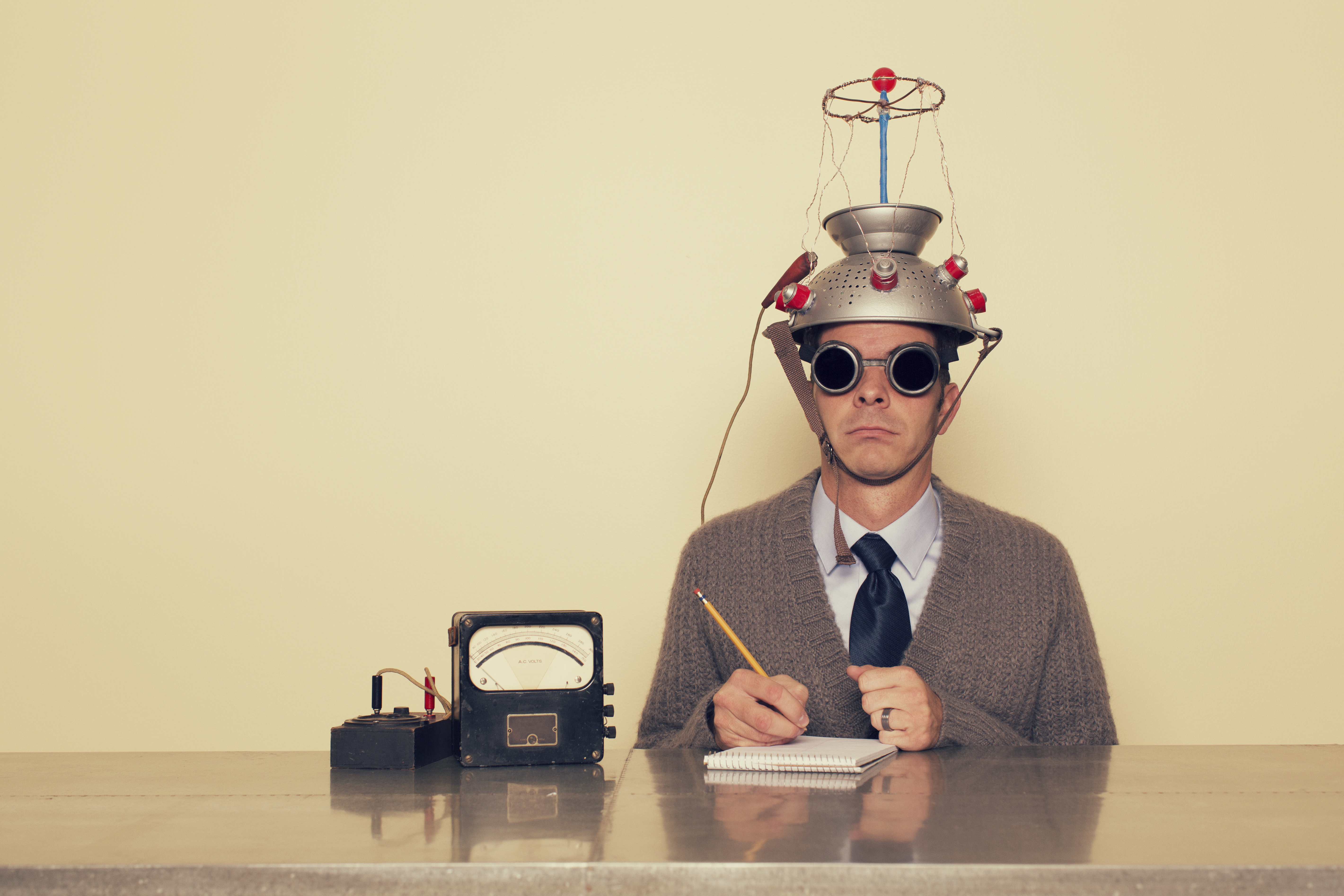 A man in a thinking cap with a pencil and paper ready to do an experiment.