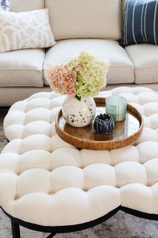 rounded living room footstool with tray and vase of flowers