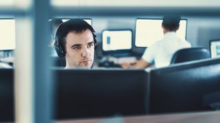 man sat working at computers with headphones on