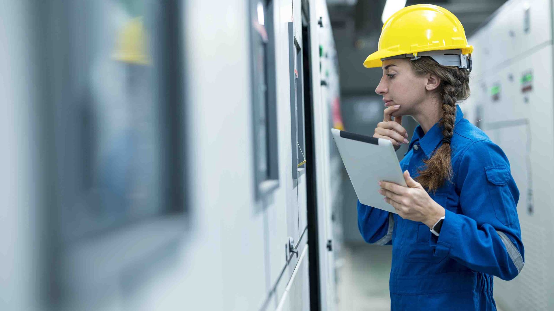 Photo of a woman in a hard hat looking at machines