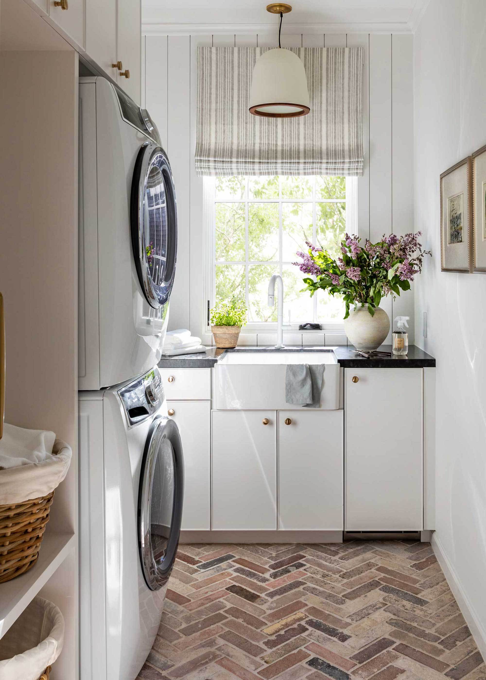 small white laundry room with herringbone brick flooring