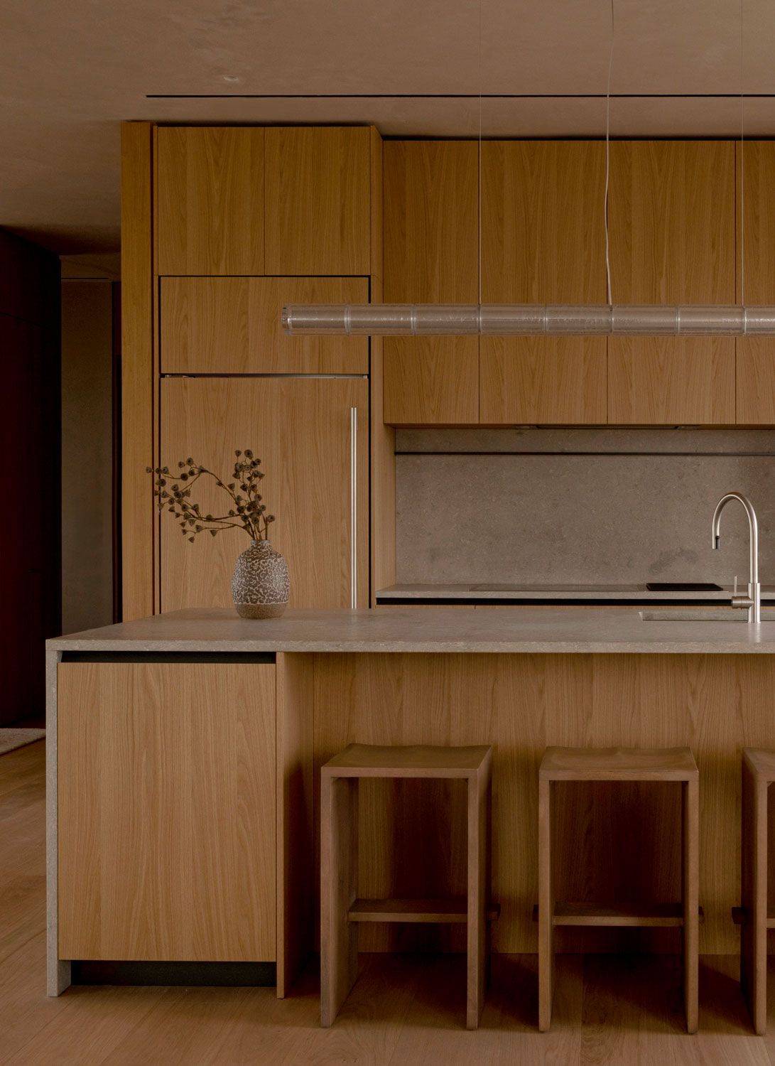 Kitchen at 262 Fifth Avenue with oak cabinetry, stone worktops, timber stools, and a minimal linear pendant light