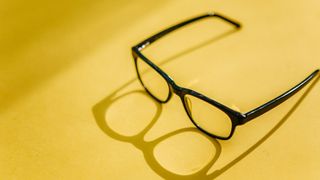 Black frame glasses on a yellow background