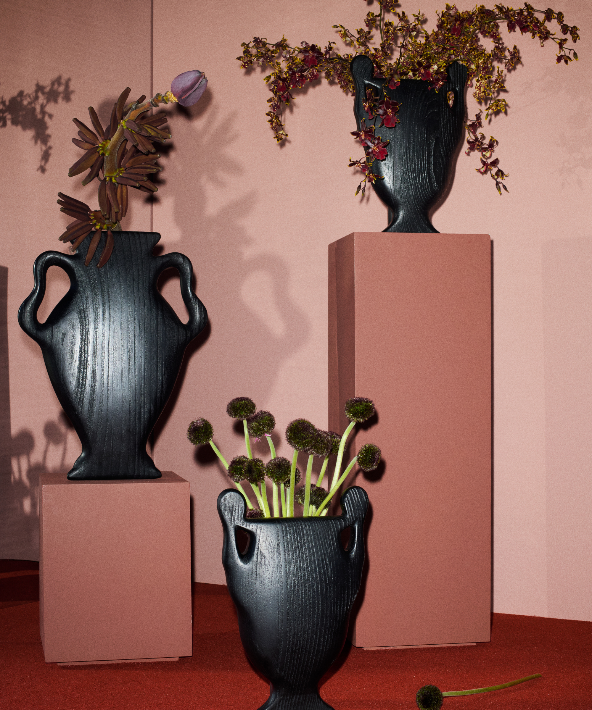 Kelly Wearstler x H&amp;amp;M Home black sculptural vases pictured in a rose-colored room with red carpet.