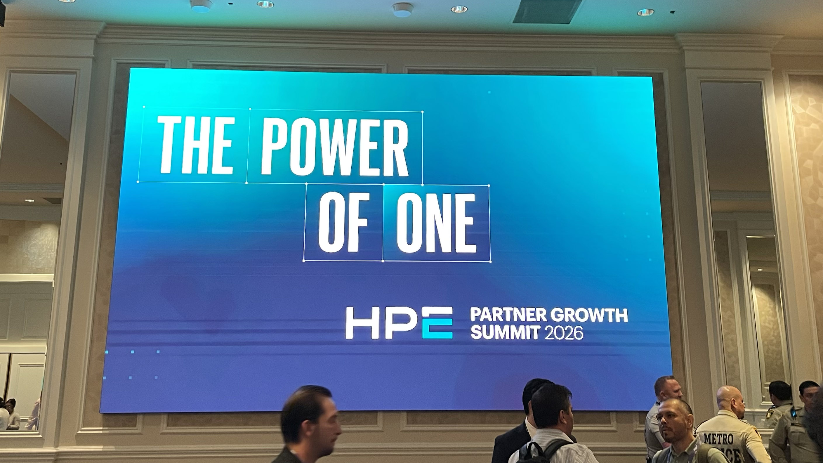 A sign saying "The Power of One HPE Partner Growth Summit 2026" on the wall of the Venetian Conference Center in Las Vegas at HPE Discover 2026. There is a handful of people in the foreground.
