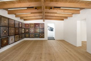 White room with wooden ceiling slates and a wall of paintings