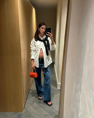  @jaimeridge wearing white button-down, jeans, and red bag.