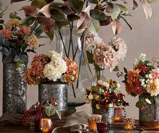 Autumnal flowers in vases against a gray background.